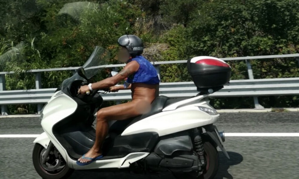 Uomo nudo sullo scooter in autostrada
