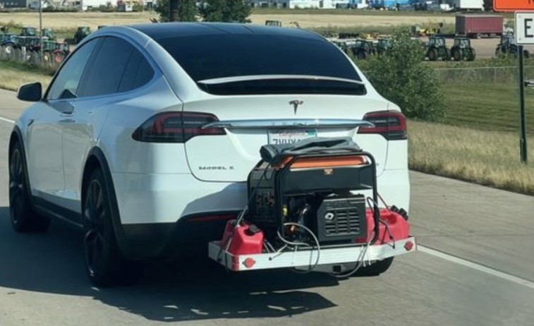 auto elettrica Tesla con un generatore di corrente al seguito per la ricarica delle batterie 